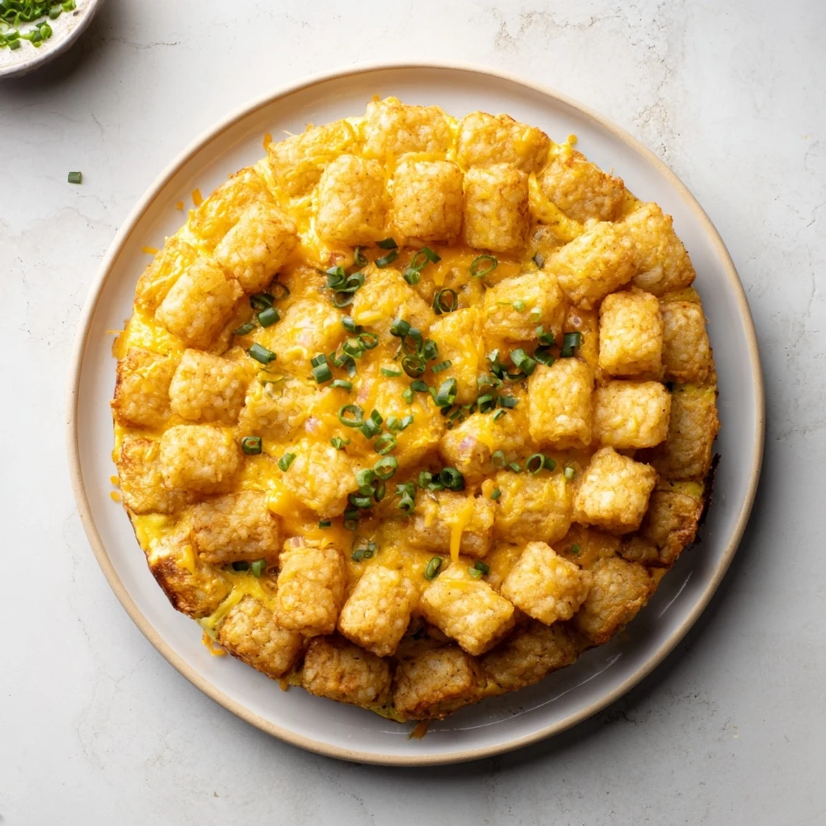 A cheesy 5-Ingredient Tater Tot Frittata, baked until golden brown and ready to serve with fresh scallions.