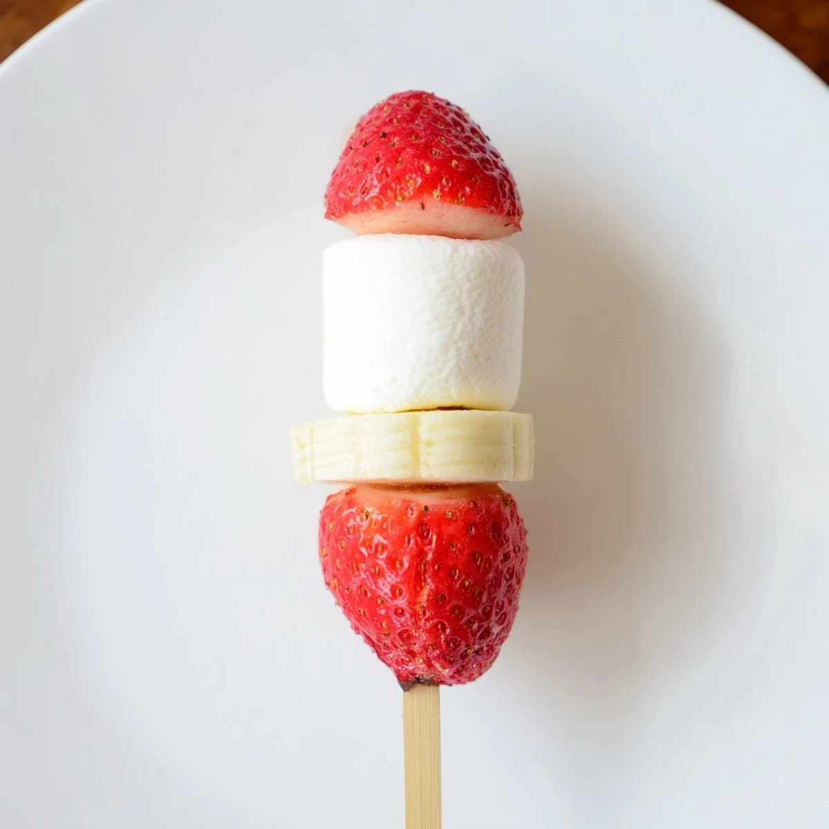 Vibrant image of Strawberry Banana Santa Sticks: red berry hats atop creamy banana rounds, ready to eat.