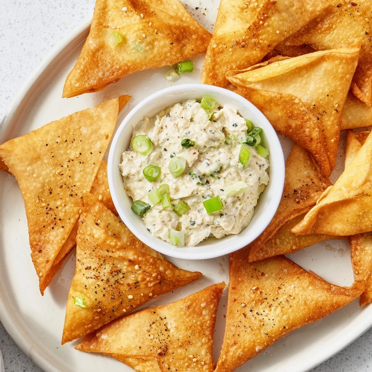 Golden air fryer lumpia chips with savory chicken cream cheese dip, a delicious party snack.