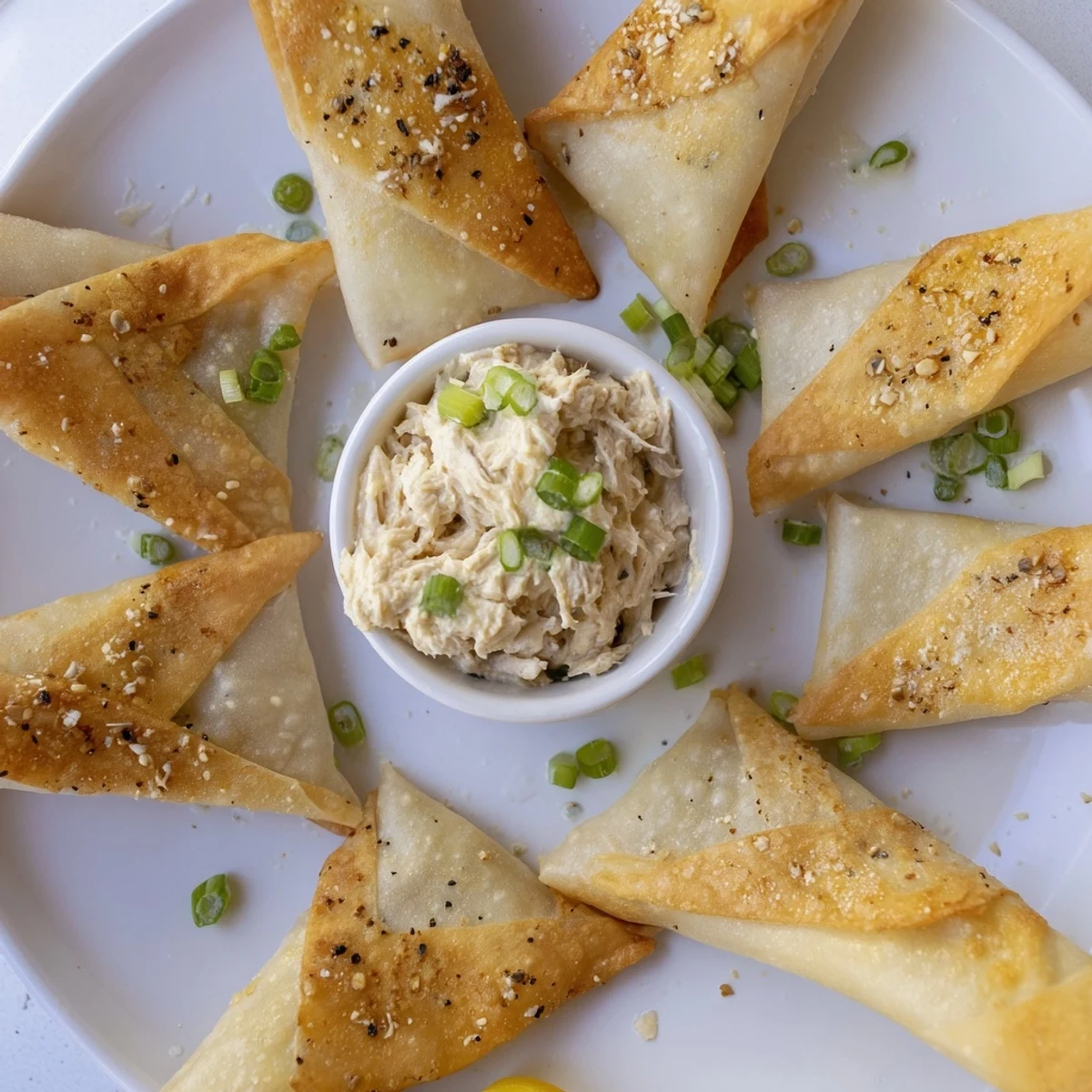 Crispy, golden-brown lumpia chips served beside a creamy chicken cream cheese dip, a Filipino appetizer.