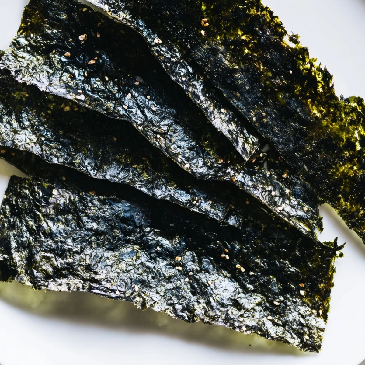 Close-up of homemade roasted seaweed chips, stacked and ready for snacking, glistening with sesame oil and a hint of salt.  