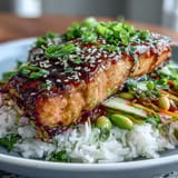 Healthy Asian-Inspired Salmon Bowl garnished with sesame seeds and colorful julienned vegetables.