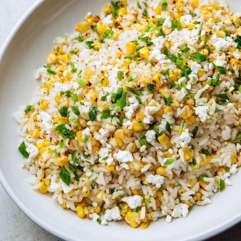 Fluffy Mexican Street Corn Rice, pictured close-up, is tossed with creamy cheese and fresh cilantro.