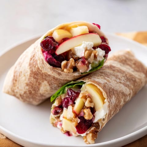 This easy Cranberry Goat Cheese & Walnut Holiday Wrap displays fresh ingredients like apple and walnuts ready for rolling.