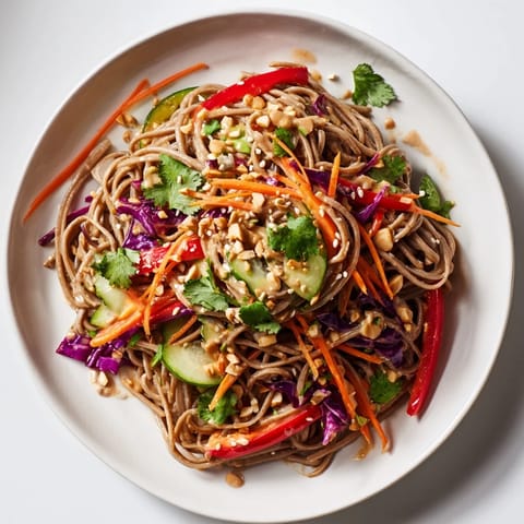 Chilled soba noodle salad tossed in a creamy peanut sauce, topped with sesame seeds and herbs.