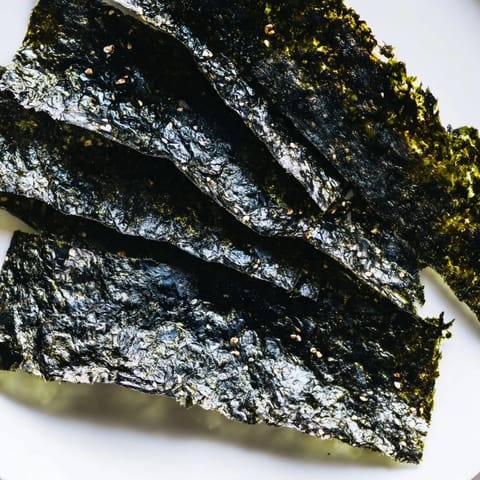Close-up of homemade roasted seaweed chips, stacked and ready for snacking, glistening with sesame oil and a hint of salt.  
