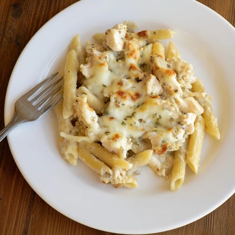 A close-up slice of Chicken Alfredo Casserole revealing tender chicken, silky Alfredo sauce, and gooey cheese in a creamy bake.