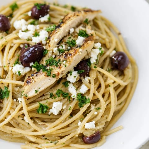 Hearty Greek Chicken Spaghetti dinner with tender sliced chicken, colorful cherry tomatoes, and feta, garnished with fresh parsley and ready to serve.