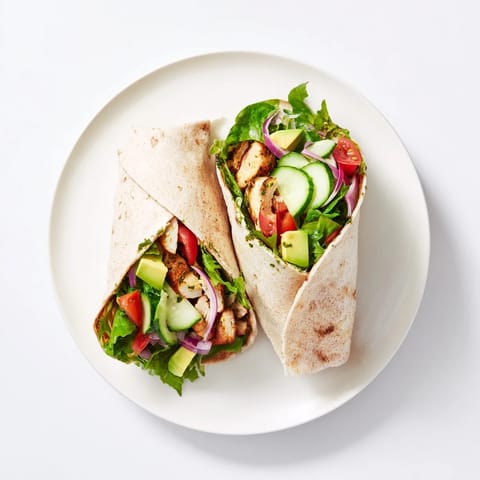 Savory chimichurri chicken salad wrap with mixed greens, cucumber, tomato, and a zesty herbaceous sauce.