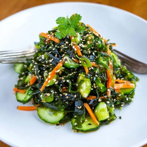 A chilled bowl of seaweed salad garnished with sesame seeds and fresh cilantro, perfect for summer.  