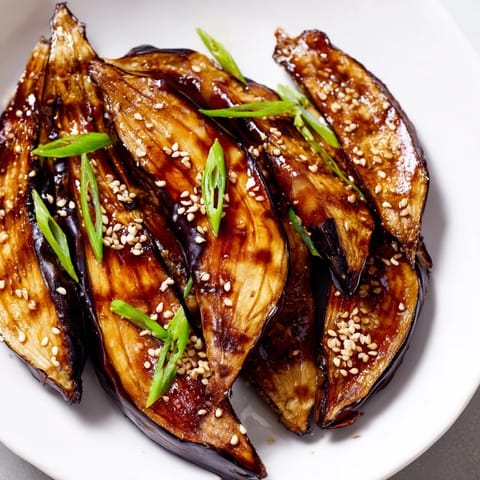 Roasted Japanese eggplant brushed with a thick, sweet-savory miso glaze, garnished with fresh green onions for an umami-rich side.