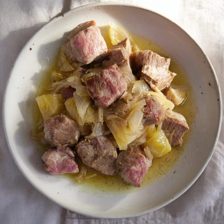 A steaming bowl of effortless pork and sauerkraut stew, garnished with fresh herbs, is ready to be served.