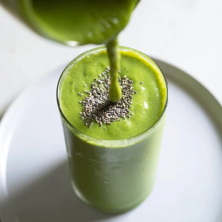 A close-up of a vibrant Spinach Avocado Smoothie, thick with blended fruit and greens.