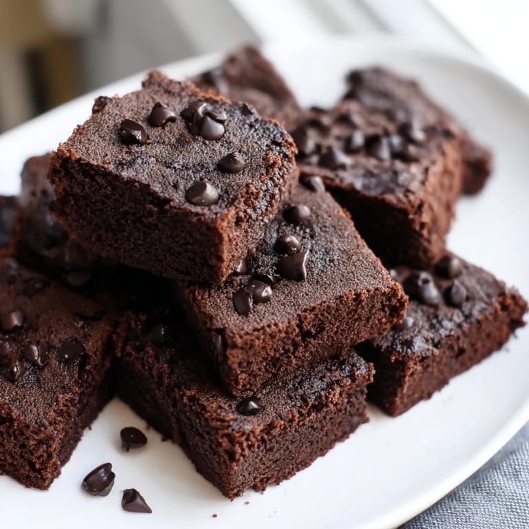 These homemade Greek yogurt brownies appear moist, with visible chocolate morsels for a satisfying treat.