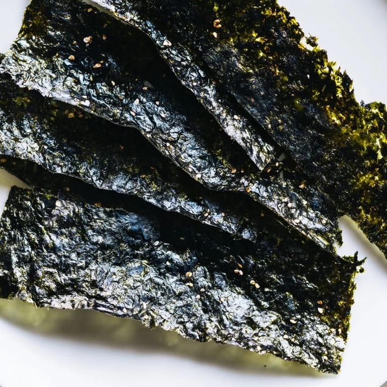 Close-up of homemade roasted seaweed chips, stacked and ready for snacking, glistening with sesame oil and a hint of salt.  