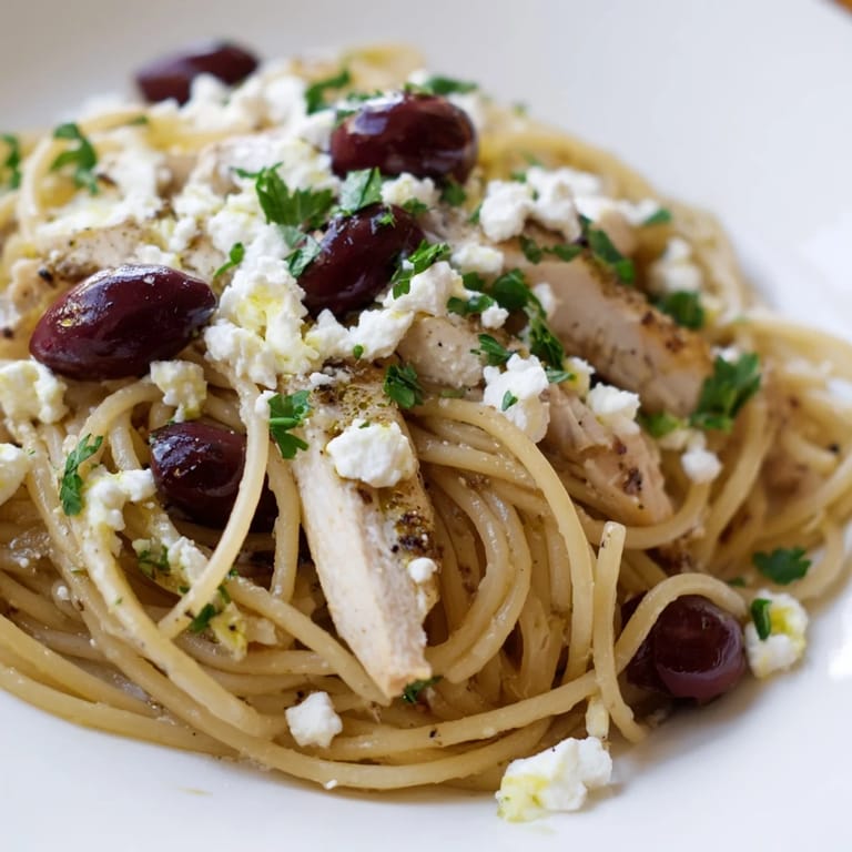 Steaming Greek Chicken Spaghetti served with a forkful of al dente pasta, briny olives, and crumbled feta for a Mediterranean weeknight meal.