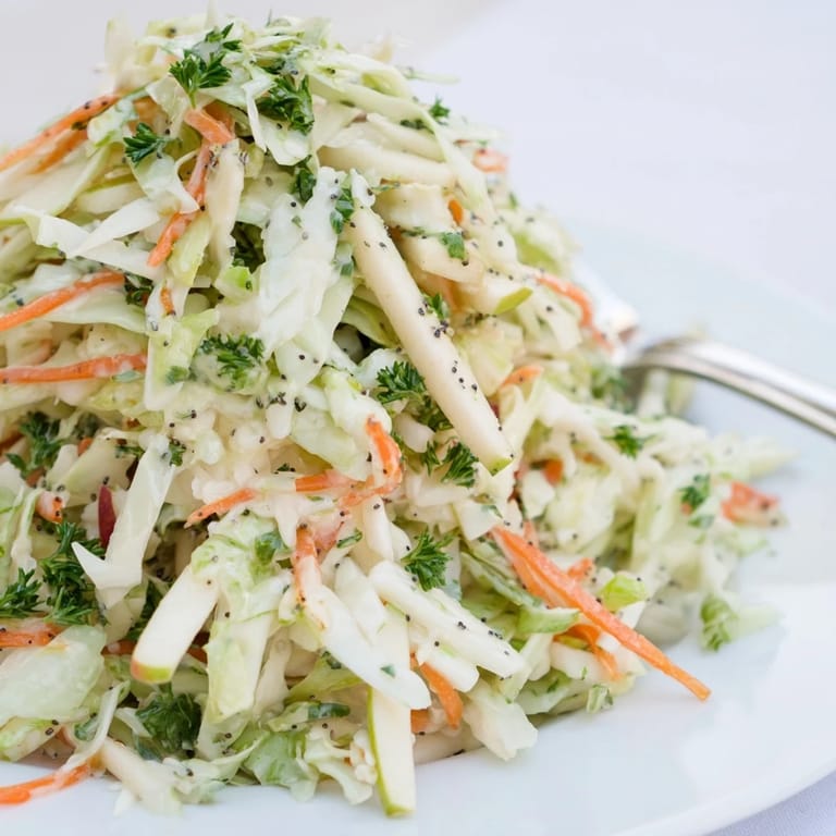 A refreshing, crunchy Green Cabbage and Apple Slaw served in a white bowl with fresh parsley.
