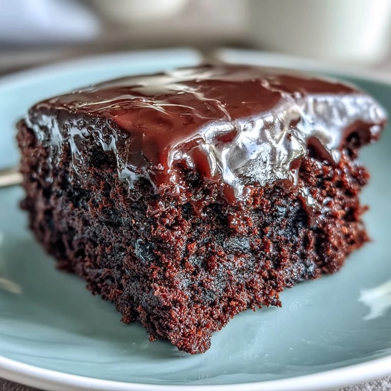 Homemade Easy Chocolate Fudge Cake with dense, fudgy crumb and glossy chocolate icing on a cooling rack.