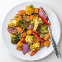 Golden Anti-Inflammatory Turmeric Roasted Vegetables on a baking sheet, featuring vibrant cauliflower, broccoli, and sweet potatoes with crispy edges.  
