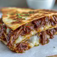 Cinco de Mayo birria quesadillas with consommé dip, golden crispy tortillas filled with tender braised beef and melted cheese.